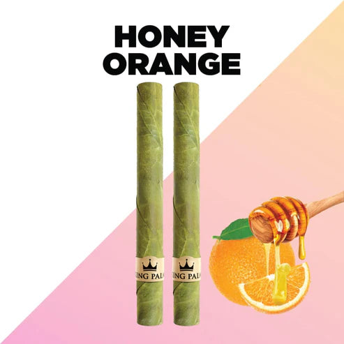 Two green rolled items with a 'King Palm' logo, an orange slice, and honey being drizzled on it against a pink and white background.