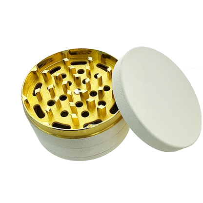 Gold and white herb grinder on a white background
