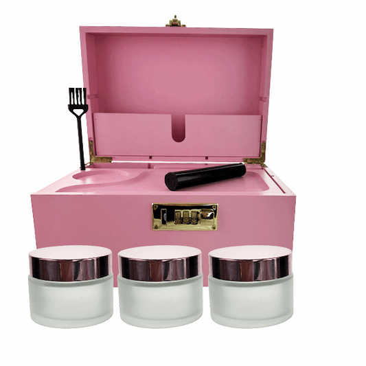 Pink jewelry box with three white jars and a black fork on a white background
